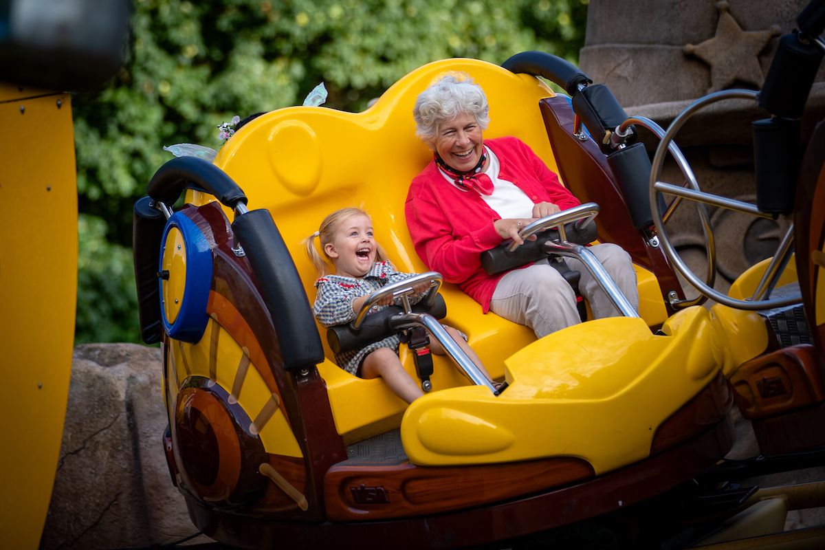 Oma en kleindochter lachen samen in een gele attractie in de Julianatoren.