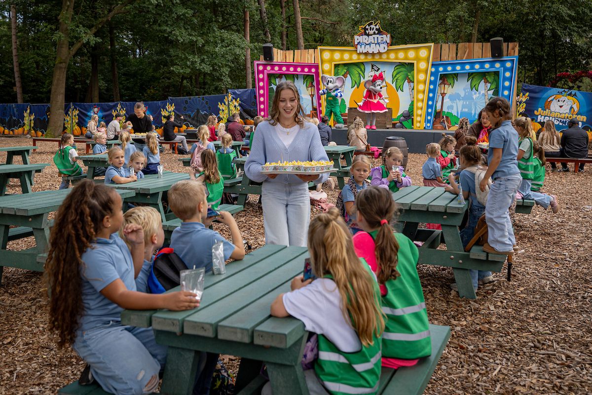 Klassen lunchen aan de picknicktafels bij het podium van de Julianatoren